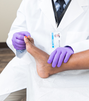 Closeup of healthcare provider examining man's foot.