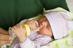 Newborn baby being fed formula in special bottle..