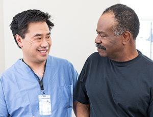 Health care provider talking to man in exam room.